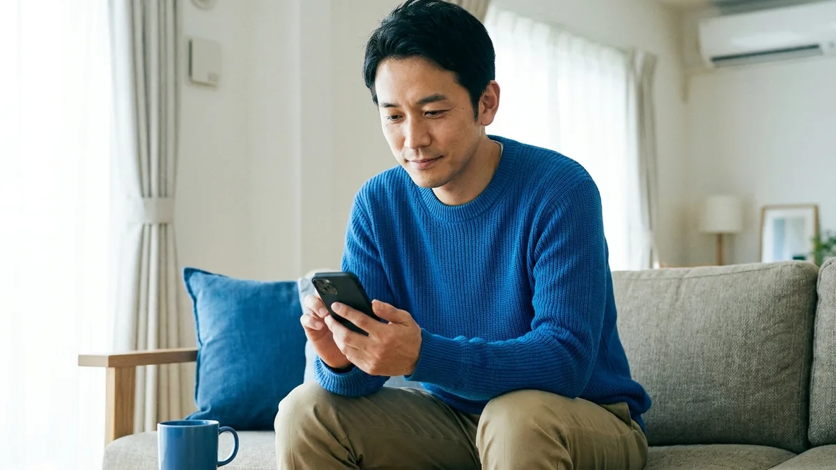 自宅でスマートフォンから医師のオンライン診察を受ける男性のイメージ